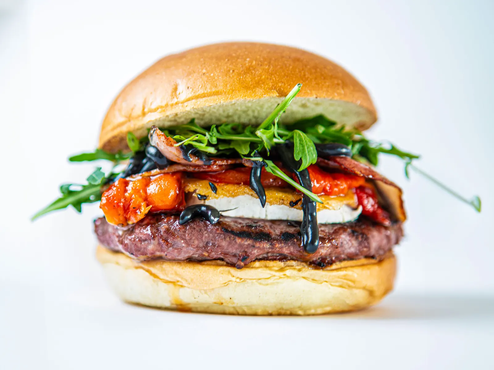 Hamburguesa Campestre con queso de cabra a la plancha, pimientos asados, rúcula y allioli de ajo negro