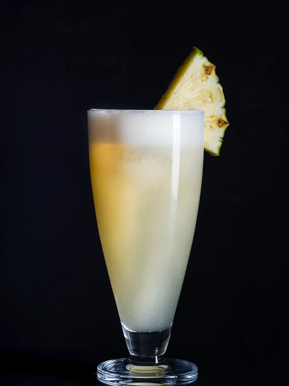 Piña colada en vaso alto con una rodaja de piña