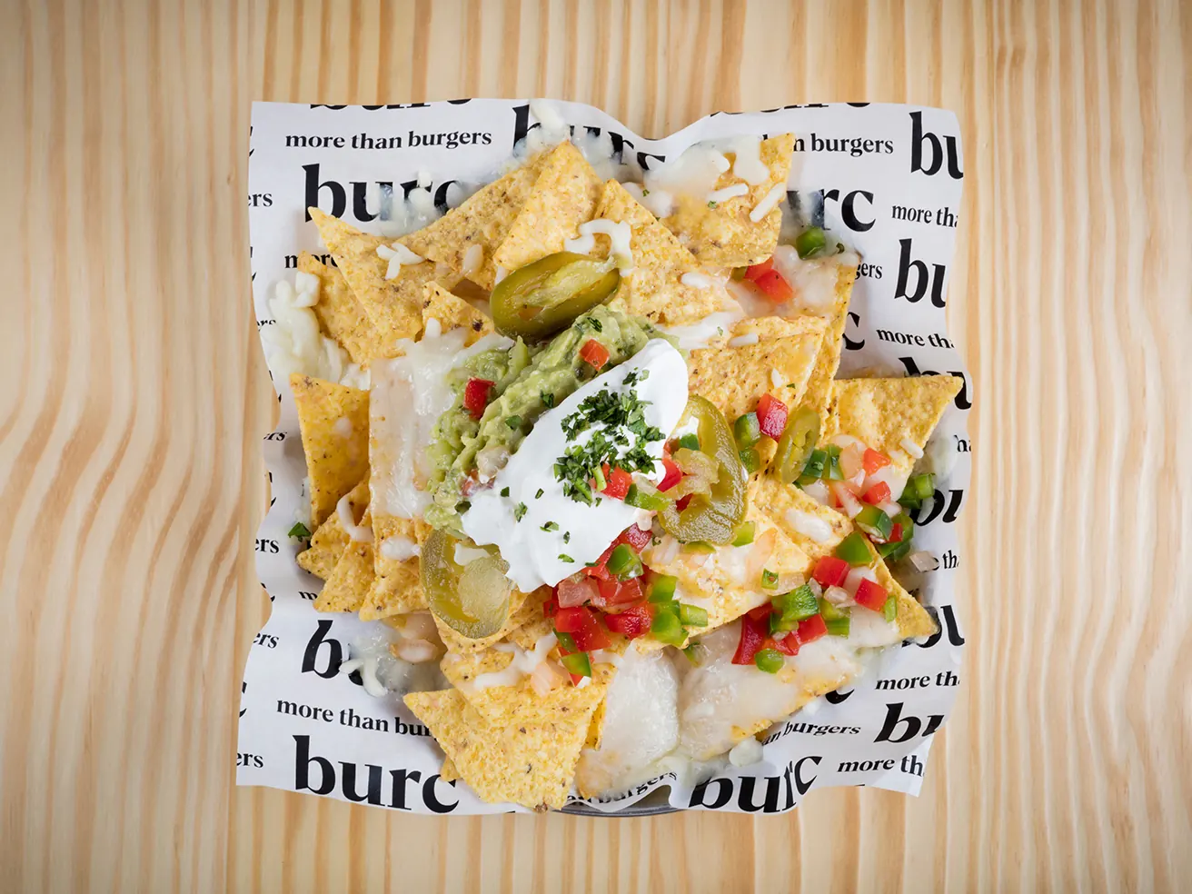Nachos Burc con guacamole y pico de gallo, servidos sobre el papel estampado de la casa